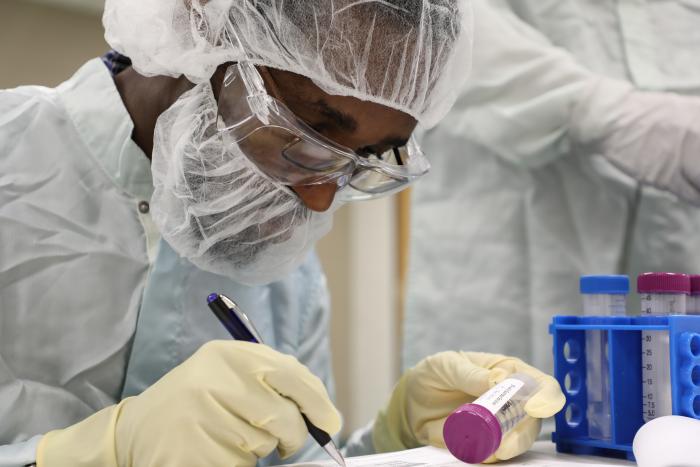 person in PPE looking down at bottle 