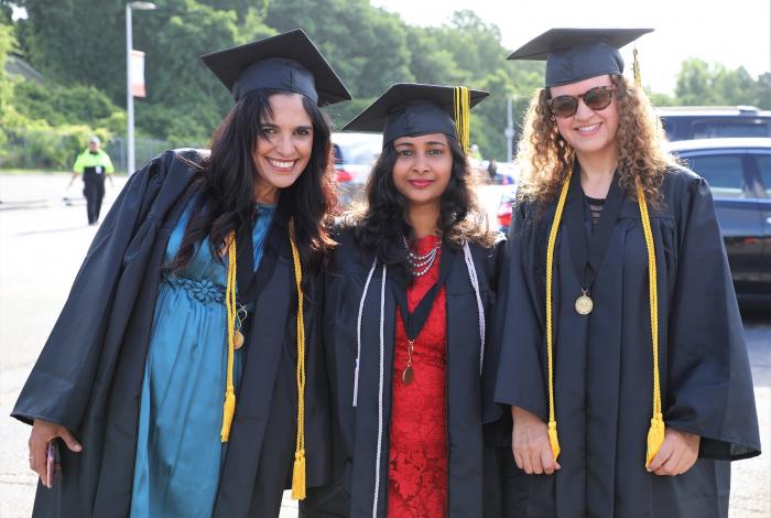 three woman in cap and gowns smiling