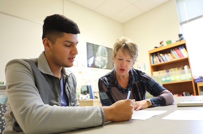 student and tutor sit together at table