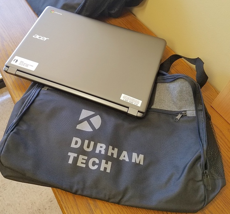laptop laying underneath a laptop bag with Durham Tech logo