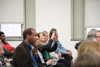 Those attending the celebration listen and take photos of the speakers.