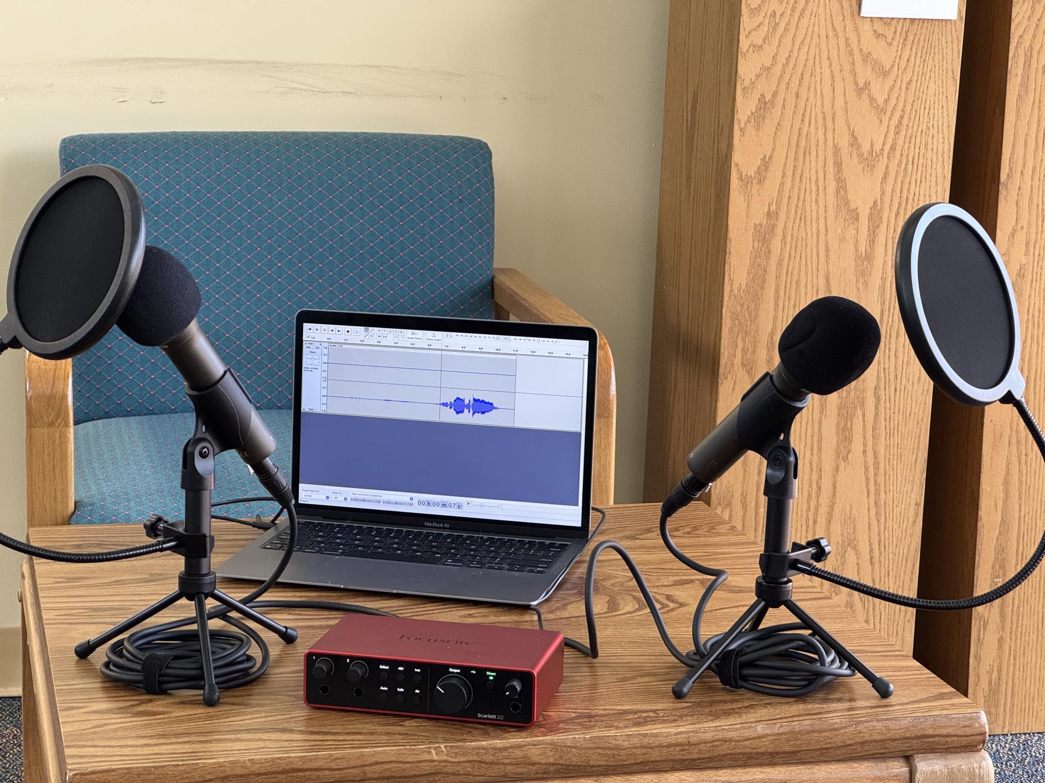 An open bag holding two microphones, XLR cables, and an audio interface.