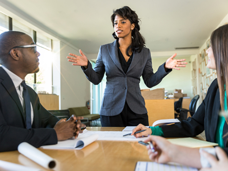 A business person stands in front of a group during a board meeting.