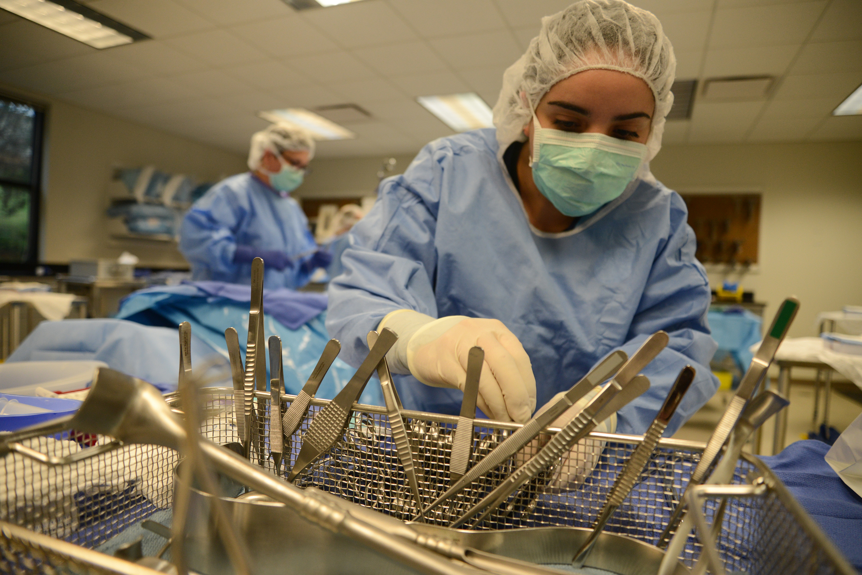 student with surgical mask and gloves looking over surgical tools