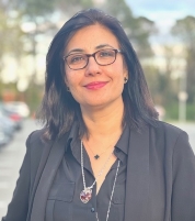 Dr. Farwa Hussein Shah wearing a black button-up shirt and a professional black jacket.