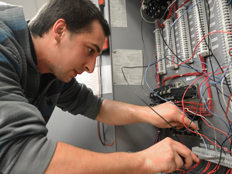 student screwing wires into an electrical board