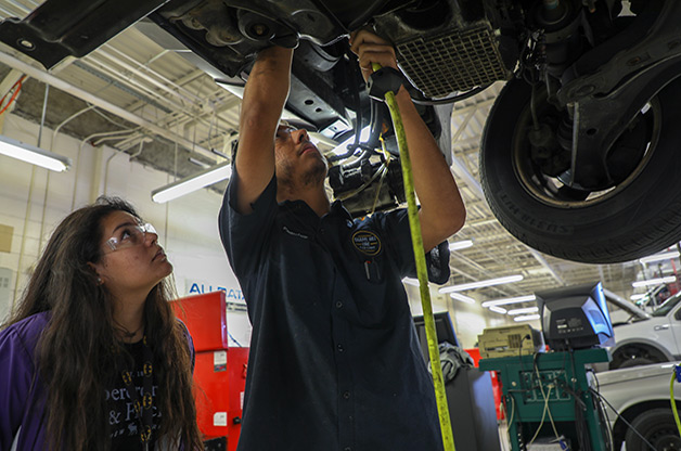 automotive students working on the undercarriage of a car