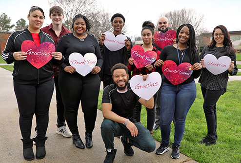 group of student scholarship recipients hold hearts with Thank you written in different languages