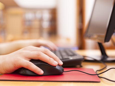 hands using computer mouse with screen behind them