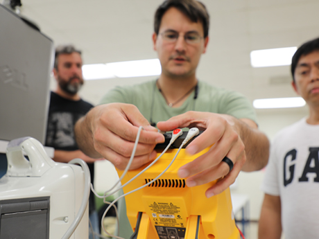 student plugging leads into a piece of biomedical equipment
