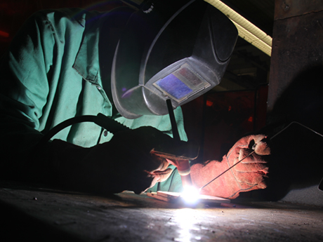 welding student wearing helmet and torching metal