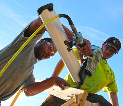 carpentry students use a power hammer to create a building frame