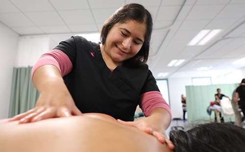 A student gives a back massage to a clinic patron