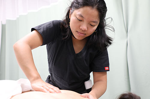 massage therapy student pressing down on client's back