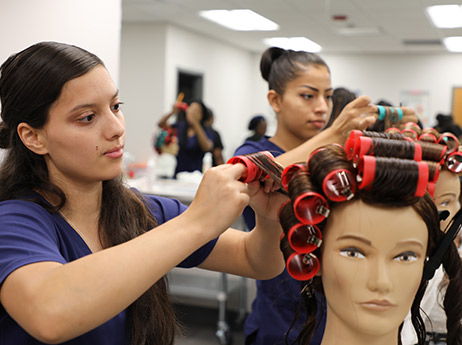 cosmetologist applying eyeshadow to a female with hair pinned up to add waves