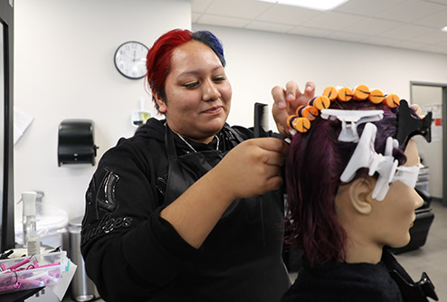 cosmetology student practices putting hair in foam curlers