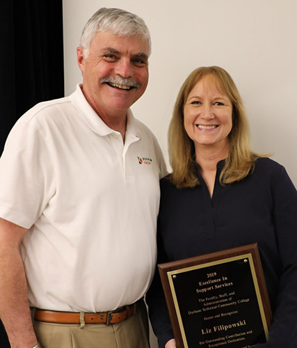 Liz Filipowski, holding plaque, poses with President Ingram