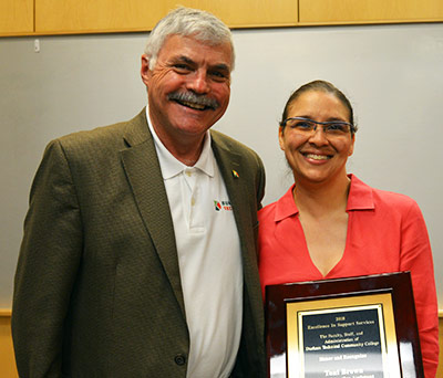 Toni-Brown, holding plaque, poses with President Ingram