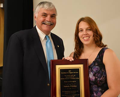 Valerie-Whitley, holding plaque, poses with President Ingram