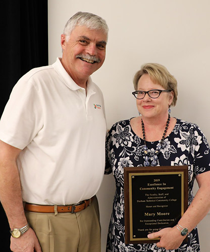 Mary, holding her award plaque, poses with President Ingram