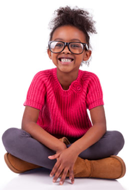 A smiling young girl wearing glasses and sitting cross legged