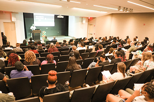 a large group of students listen to a speaker in an auditorium