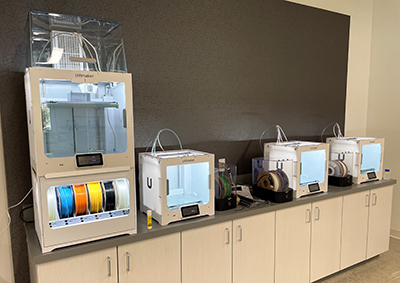 3D printers aligned in a row on a work bench