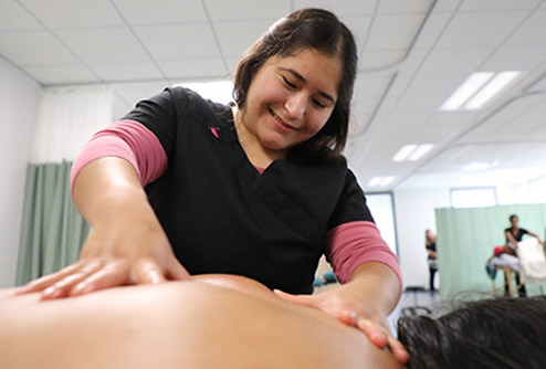 student practices giving a full body massage in clinic