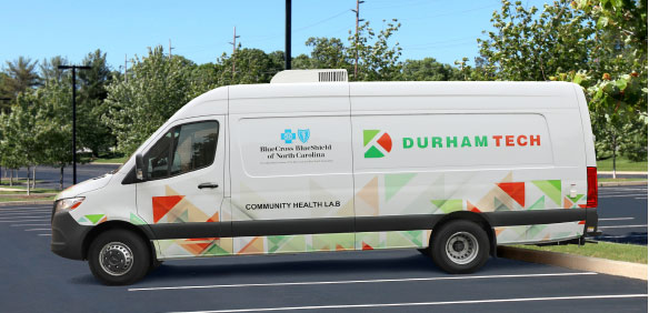 A white van in a parking space with the Durham Tech logo and Community Health Van on the side