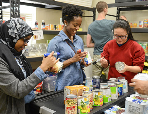 studen volunteers mark donations and stock shelves in the food pantry