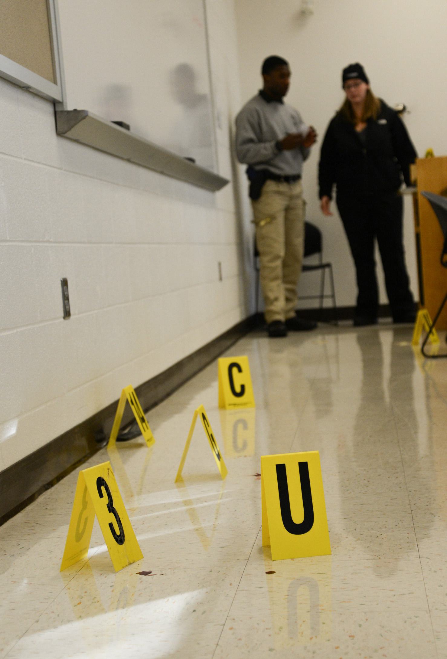 yellow number markers on ground to identify evidence and two people standing in background