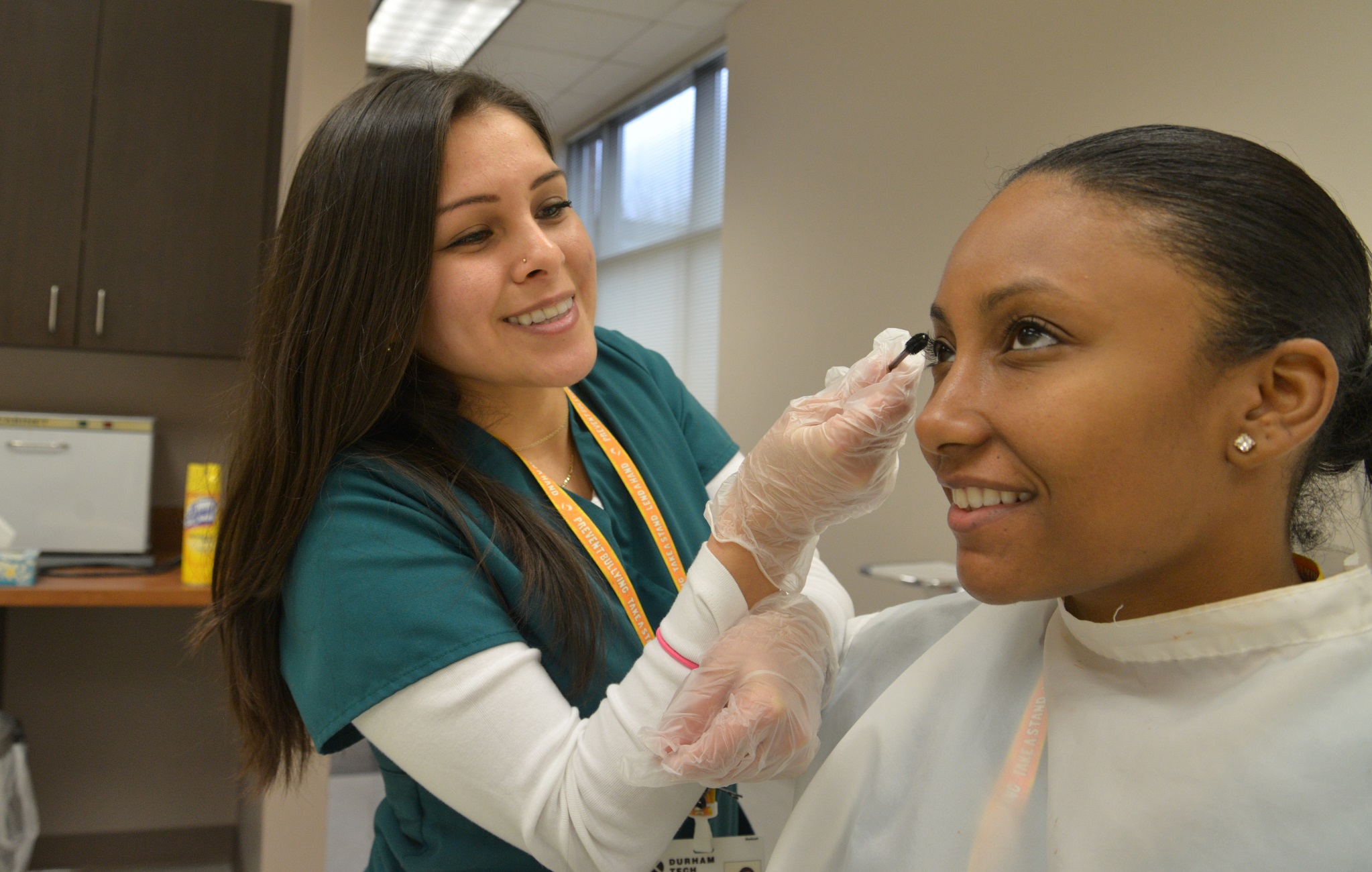 student putting mascara on another student in esthetician lab