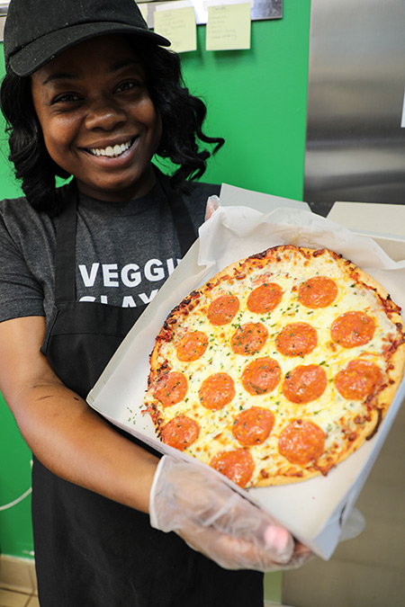 student cafe employee holds up personal pizza