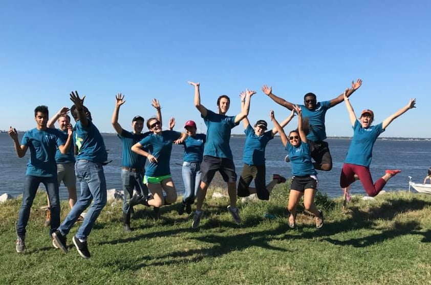 group of students jumping into the air on waterfront