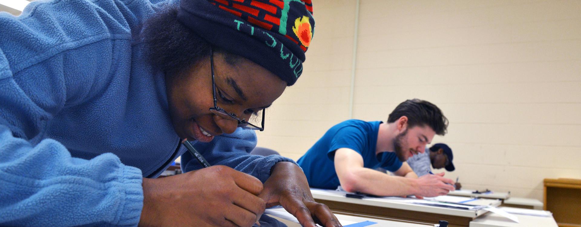 A Durham Tech student holds a pencil and focuses on work in a classroom
