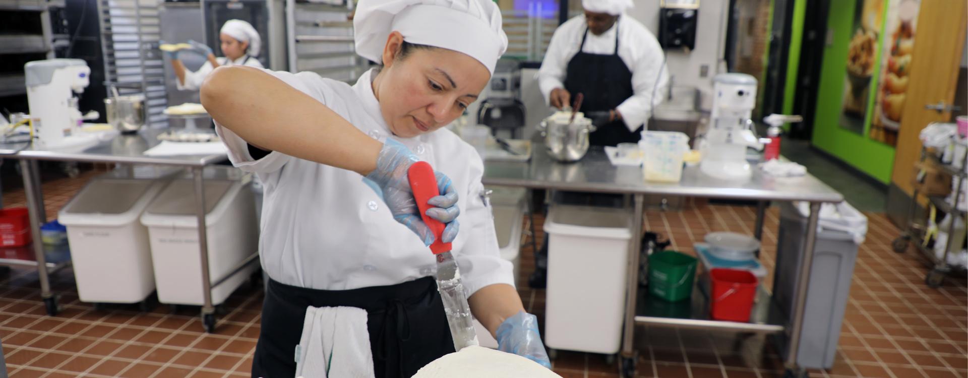 culinary student frosts a cake in the professional kitchen
