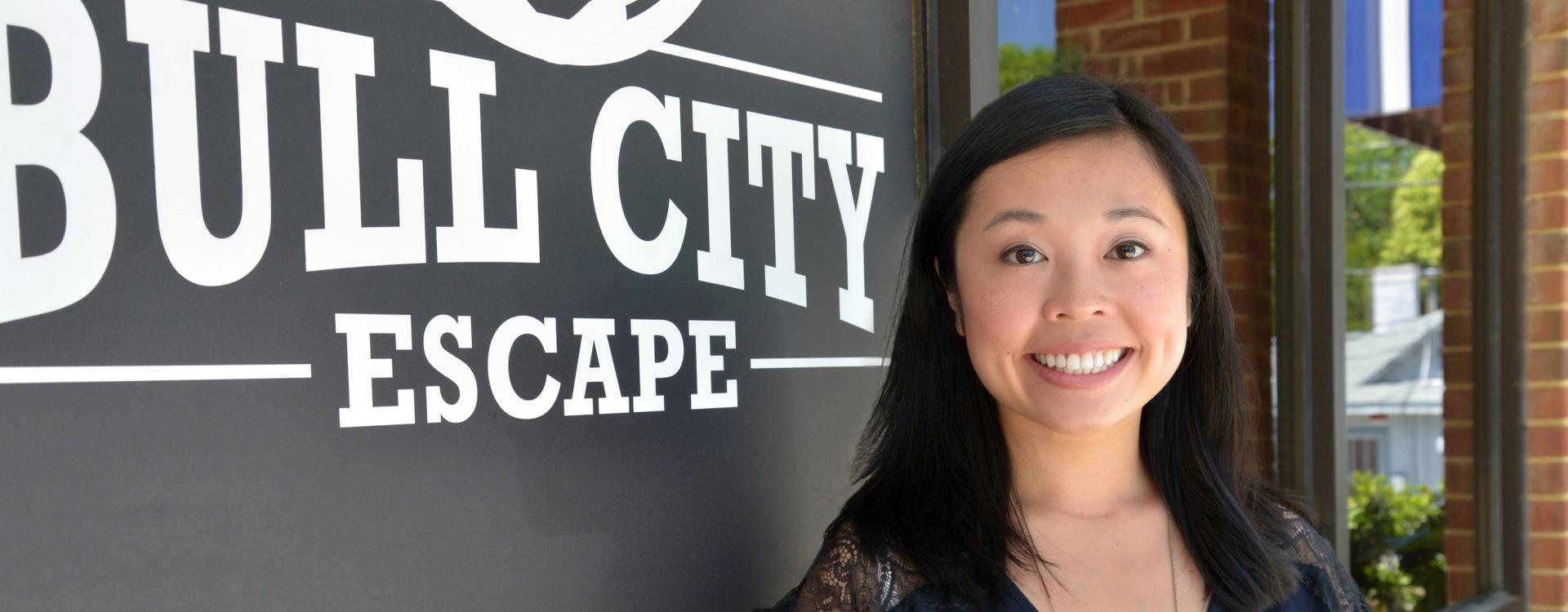 female business owner stands in front of Bull City Escape sign