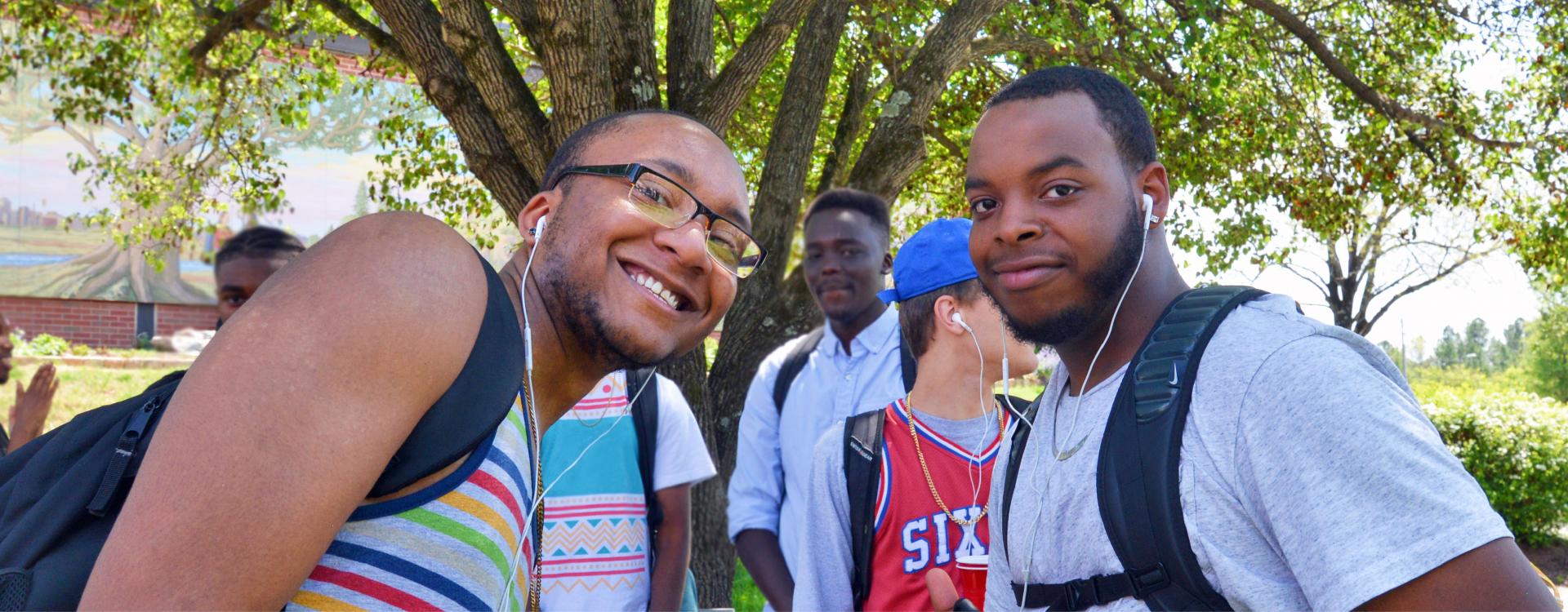 two students on main campus plaza outside smiling at camera