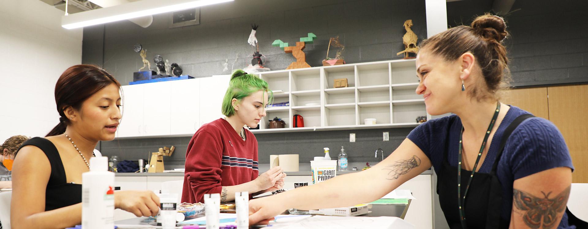 instructor converses with students about their painting projects in the fine arts studio