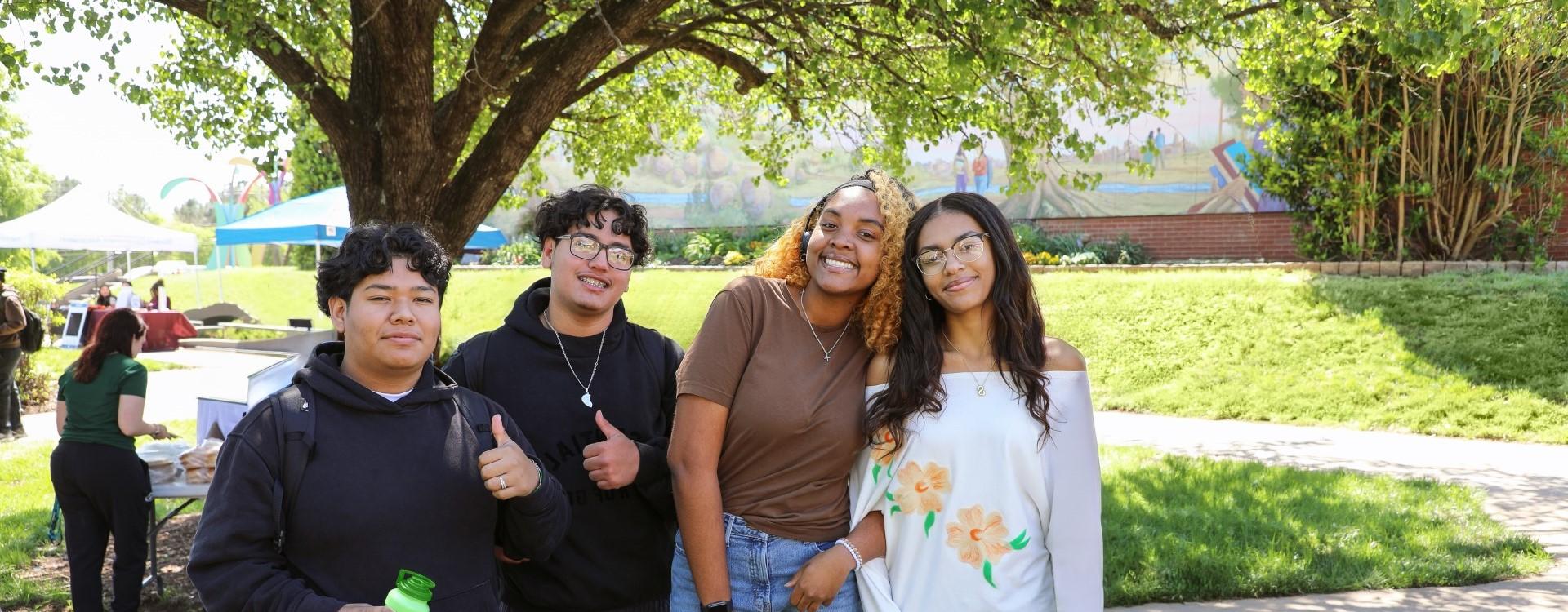 Four students smiling together in the Campus Quad Area during a Spring Fling event