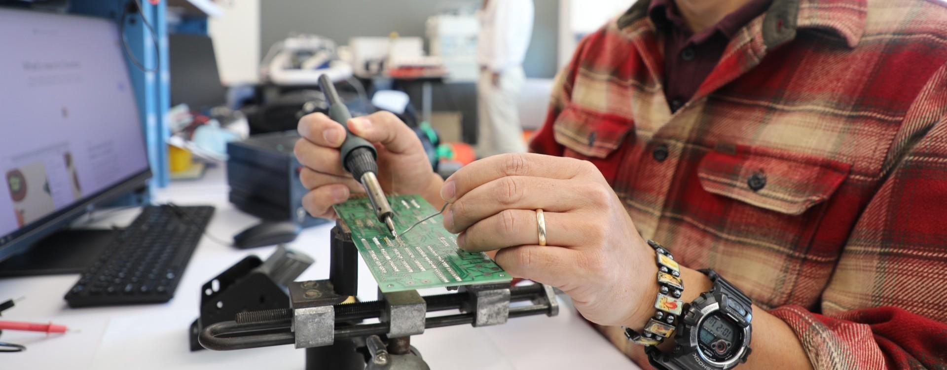 student working with a soldering set to build a PCB
