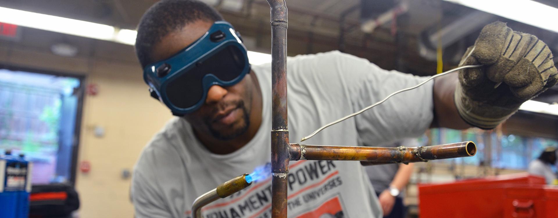 student welds a pipe in plumbing class