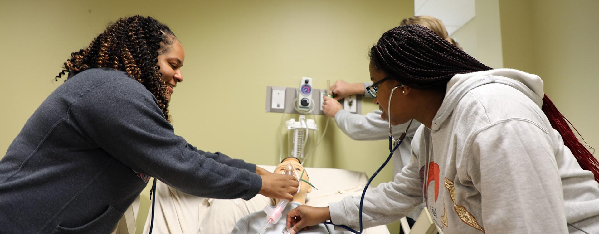 respiratory therapy students practice applying oxygen and listening to a patients breathing in lab