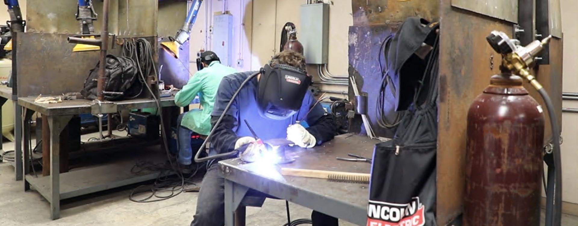 welding student wearing a mask and using a torch