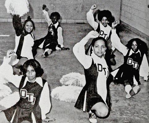 eight DTI cheerleaders in uniforms pose in formation