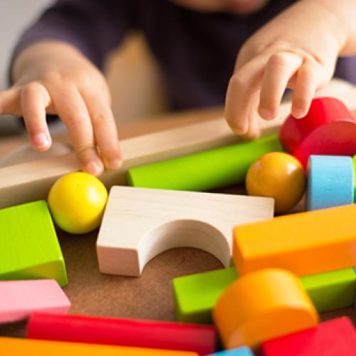 child's hands playing with block toys 