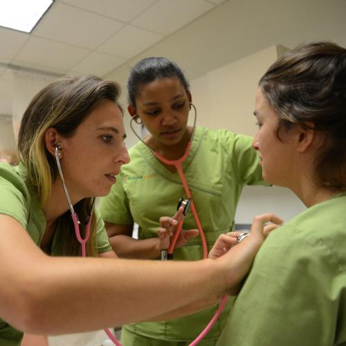students practicing the use of a stethoscope on another student