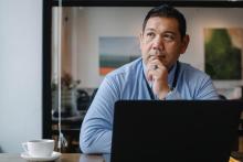 Man sitting behind laptop and deep in thought