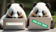 Two panda bears sitting side by side while working on laptop computers.