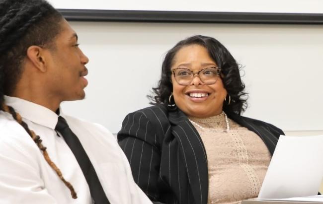 A student wearing a dress shirt and tie speaking with their teacher during a mock business interview